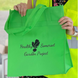 photo of person holding green bag with Health Somerset Garden Project's logo on it